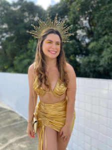 Mulher sorridente pousando para foto com roupa de carnaval dourada